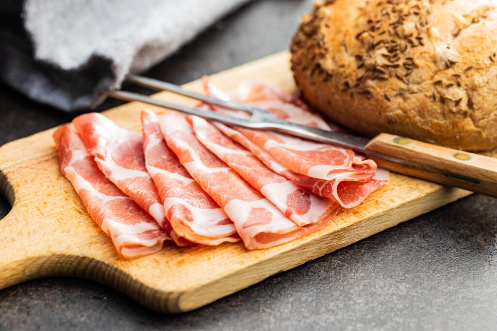 Italian dried ham. Coppa Stagionata on cutting board.